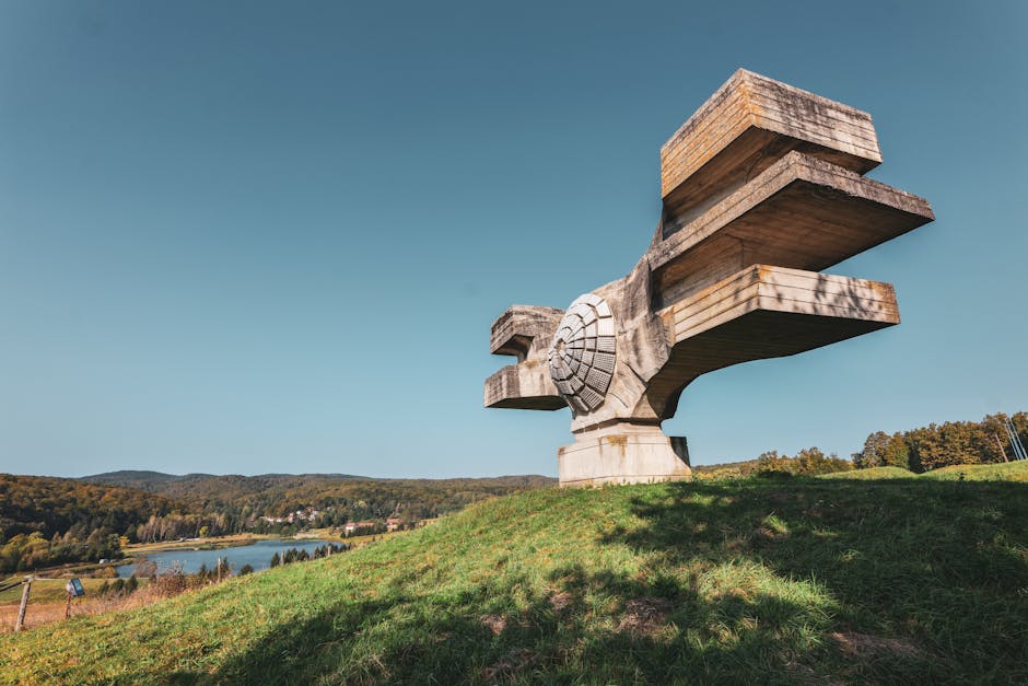 Spomenik Revolution in Podgarić amidst rolling hills and clear skies.