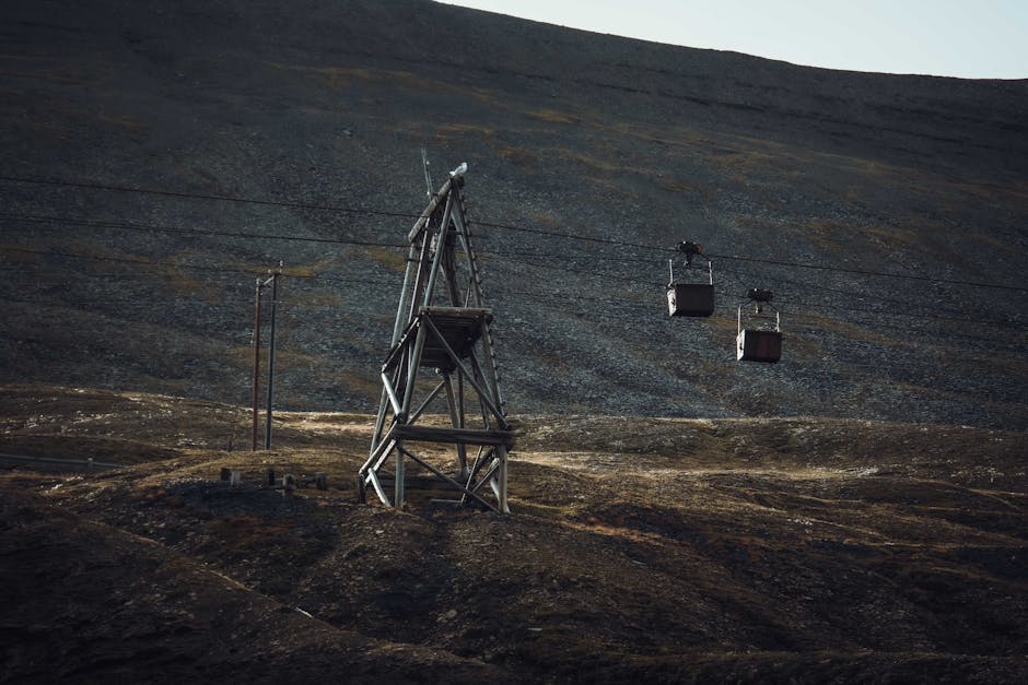 Historic cable car towers in a rugged, barren landscape under a dim sky.